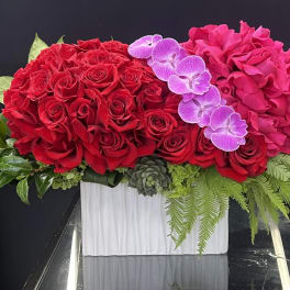 Red roses and pink hydrangeas with purple orchids in a white vase