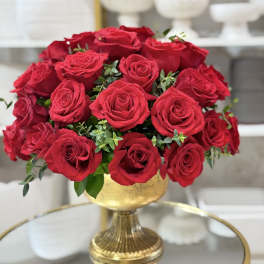 Red roses arranged in a gold pedestal vase