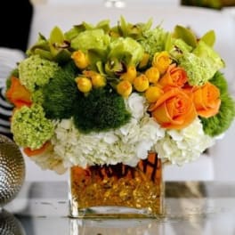 Orange roses and green blooms in a square glass vase