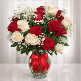 Red and white roses in a glass vase with a red ribbon