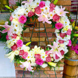 Large floral wreath with pink roses, white daisies, and lilies on an easel