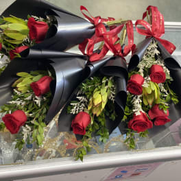Several red rose bouquets wrapped in black paper with red ribbons