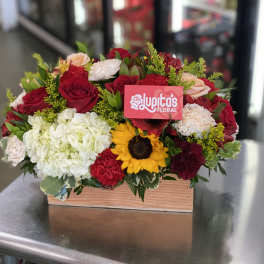 Mixed bouquet in a wooden box with red roses, white hydrangea, and a sunflower