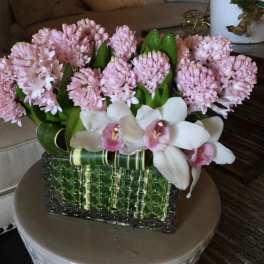 Pink flowers and white orchids arranged in a green glass vase