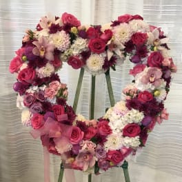 Heart-shaped floral wreath with pink and white flowers on an easel