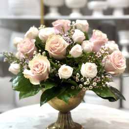Pink and white roses arranged in a gold pedestal vase