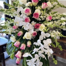 Tall floral arrangement with pink roses, white orchids, and white carnations