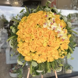 Large yellow rose arrangement with pale orchids and greenery