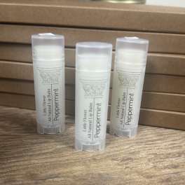 Three peppermint lip balm tubes on a wooden surface