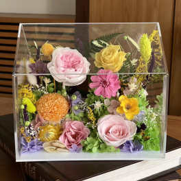 Mixed flowers arranged in a clear acrylic box