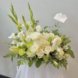 White floral arrangement with calla lilies, roses, and lilies in a vase