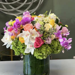 Colorful bouquet of orchids, roses, and hydrangeas in a glass vase