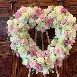 Heart-shaped floral arrangement with pink and white roses on an easel