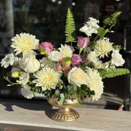 White and pink flowers arranged in a gold pedestal vase