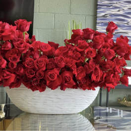 Large arrangement of red roses in a white bowl vase