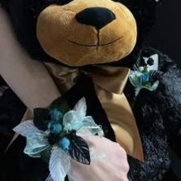 Plush teddy bear with a blue floral ribbon accessory
