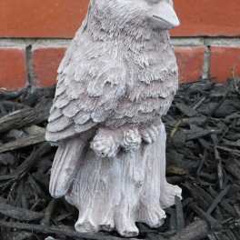 Small bird-shaped garden statue in front of a brick wall