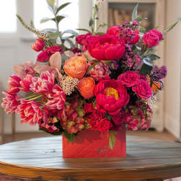 Bright mixed bouquet in a red box with pink and orange flowers