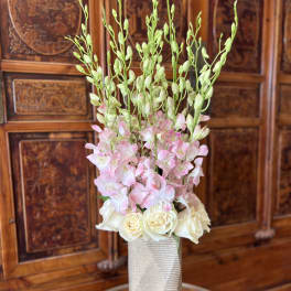 Tall floral arrangement with pink orchids and white roses in a textured vase