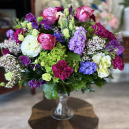 Mixed bouquet of pink, purple, white, and green flowers in a glass vase