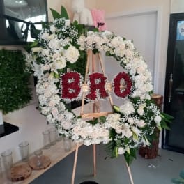 Large floral wreath on an easel with red letters in the center