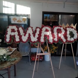 Large floral letters on easels spelling a name in red and white flowers