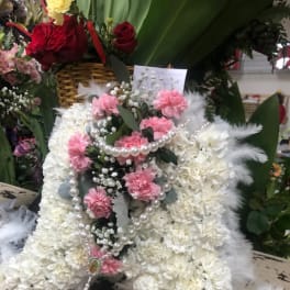 White floral funeral spray with pink carnations and pearl strands