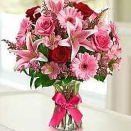 Pink and red mixed bouquet in a glass vase with a pink ribbon