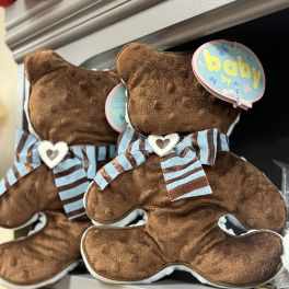 Two teddy bears with baby tags and striped bows on a shelf