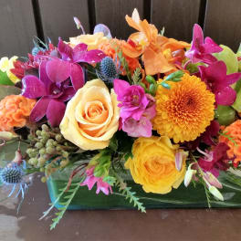 Colorful mixed flower arrangement in a rectangular glass vase
