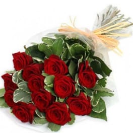 Bouquet of red roses wrapped in clear paper with a raffia bow
