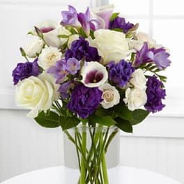 Purple and white bouquet in a clear glass vase