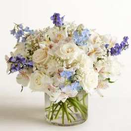 White and pale blue bouquet in a clear glass vase