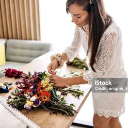 Woman arranging a colorful bouquet on a table