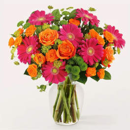 Bouquet of pink gerbera daisies and orange roses in a clear glass vase