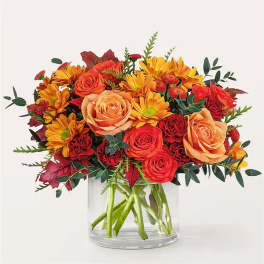 Bouquet of orange roses and yellow daisies in a clear glass vase