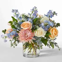 Bouquet of peach and white roses with pink chrysanthemum in a glass vase