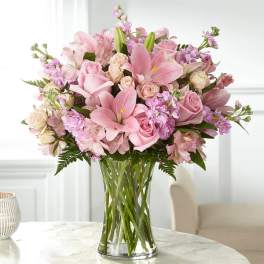 Pink roses and lilies arranged in a clear glass vase