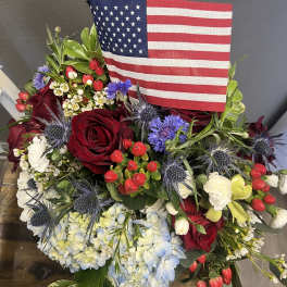 Red roses and blue hydrangeas arranged with an American flag