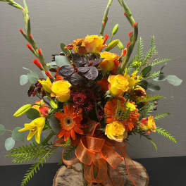 Orange and yellow mixed bouquet in a glass vase with a ribbon