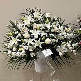White lilies and roses in a standing spray with a ribboned easel