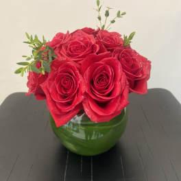 Red roses arranged in a green glass vase