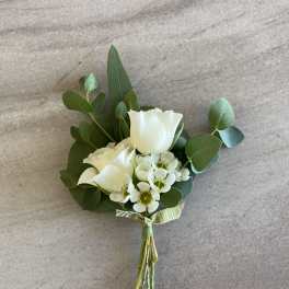 Small white rose boutonniere with tiny white accent flowers and a green ribbon tie