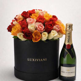 Box of multicolored roses beside a champagne bottle