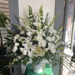Large white floral arrangement in a white vase with lilies and chrysanthemums