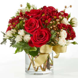 Red roses and white flowers in a glass vase with a gold ribbon