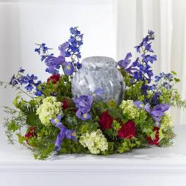 Purple and blue flowers arranged around a gray urn