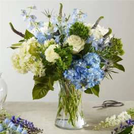 Blue and white floral arrangement in a clear glass vase
