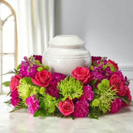 Pink roses and purple-green flowers arranged around a white urn