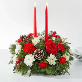 Holiday centerpiece with red candles, roses, and white flowers